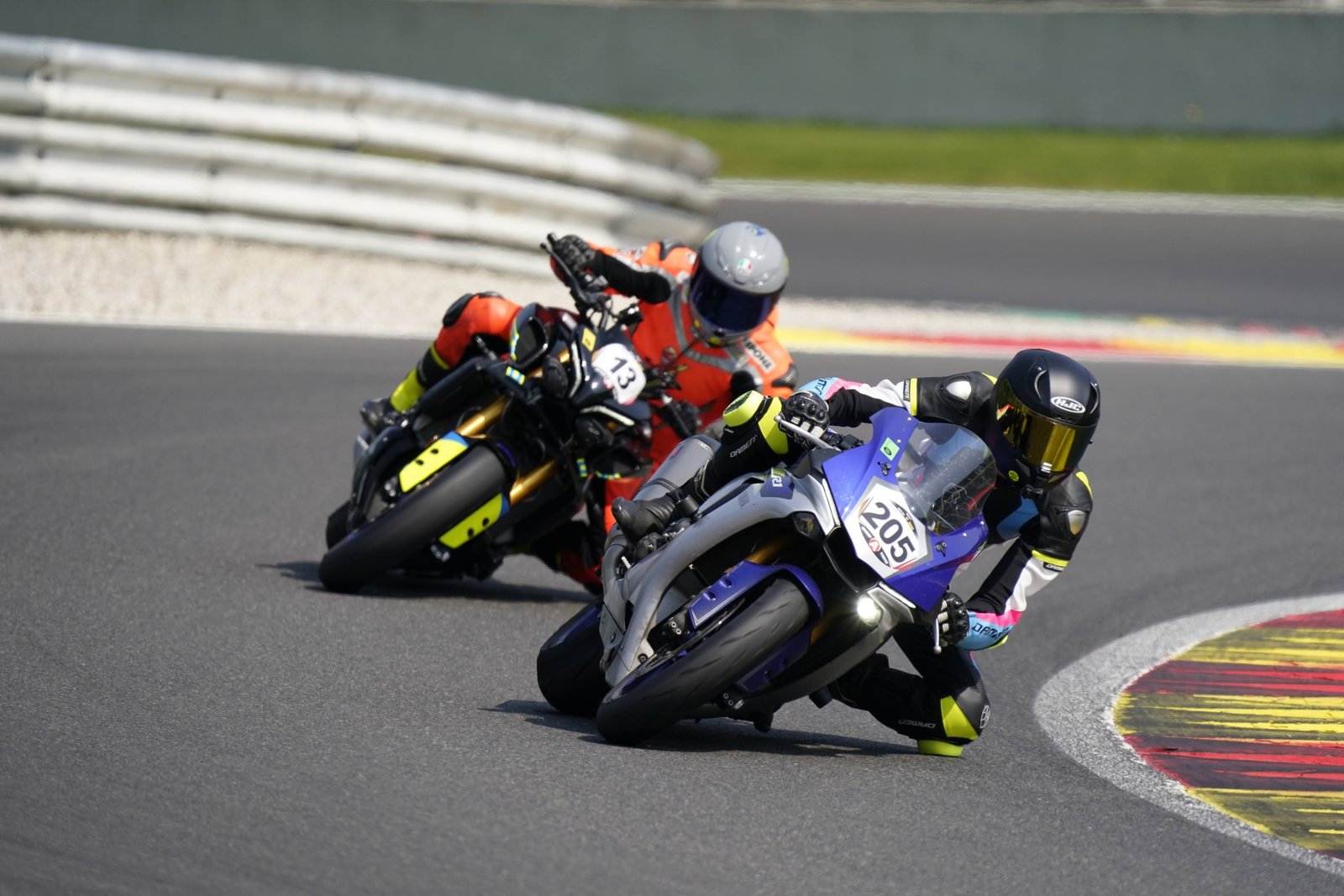 Twee coureurs op sportmotoren met de knie op de baan door een circuitbocht