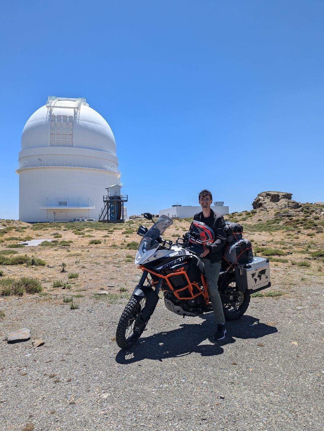 Avontuurmotor bij een sterrenwacht hoog in een droog berglandschap
