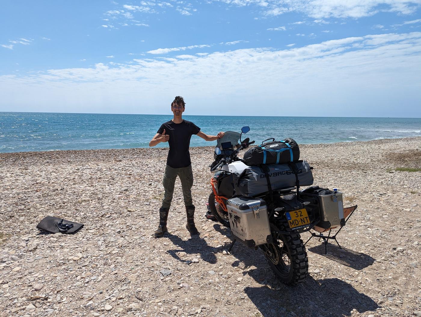Motorrijder met bepakte avontuurmotor aan de kust